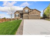 Charming two-story home featuring a stone facade, three-car garage, manicured lawn, and inviting curb appeal at 955 Horizon Ct, Erie, CO 80516