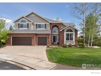 Beautiful two-story home with a well-manicured lawn and a welcoming brick facade at 14100 Doral Ct, Broomfield, CO 80023