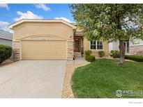 Inviting single Gathering home featuring a tan exterior, a two-car garage, and a well manicured lawn at 1810 Signature Ct, Longmont, CO 80504