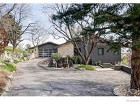 Contemporary home featuring a stone and gray exterior with a driveway, landscaping, and an attached garage at 230 Cactus Ct, Boulder, CO 80304