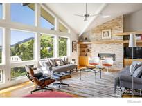 Inviting living room with vaulted ceilings, stone fireplace and large windows showcasing mountain views at 230 Cactus Ct, Boulder, CO 80304