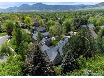 Beautiful aerial view of a suburban home surrounded by lush greenery and mature trees, with mountains in the background at 2672 Winding Trail Dr, Boulder, CO 80304