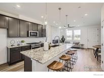 Modern kitchen features a large island with granite countertops, seating for four, and stainless steel appliances at 2729 Bear Springs Cir, Longmont, CO 80503