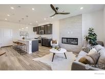 Open-concept living room showcases modern fireplace and flows into a kitchen with a large center island at 2729 Bear Springs Cir, Longmont, CO 80503