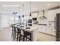 Modern kitchen with white cabinets, stainless steel appliances, and a center island with seating at 2759 Bear Springs Cir, Longmont, CO 80503