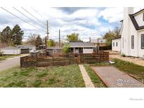 Charming home features a fenced yard, grassy lawn, and a stone patio area at 3001 Chase St, Wheat Ridge, CO 80214