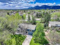 Stunning aerial view of a blue two-story home with a lush green lawn and mountain views at 4251 Peach Way, Boulder, CO 80301