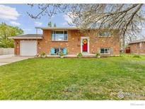 Charming brick home featuring a red front door, blue chairs, and a well-maintained lawn at 4544 W 65Th Ave, Arvada, CO 80003