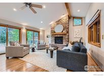 Bright living room features a stone fireplace, plush seating, and sliding glass doors to outdoor living space at 5604 Bowron Pl, Longmont, CO 80503