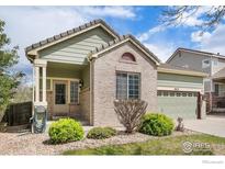 Charming one-story home with green siding, brick accents, landscaped front yard and a two car garage at 9674 Joplin St, Commerce City, CO 80022