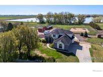 Stunning aerial view of estate featuring lake, play area, mature trees, outbuildings and a spacious yard at 111 Hunters Cove Rd, Mead, CO 80542