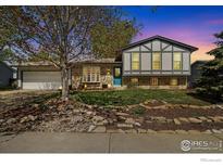 Charming two-story home with a well-manicured front yard, beautiful landscaping, and a bright blue front door at 1309 Alexandria St, Lafayette, CO 80026