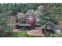 Beautiful mountain home with large windows and a deck surrounded by trees at 1629 Timber Ln, Boulder, CO 80304