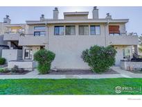 Multi-level exterior featuring stucco, balcony, front yard, and mature landscaping at 1825 Kendall St # 104, Lakewood, CO 80214