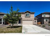 Two-story home featuring a two-car garage, a well-kept lawn, and tasteful exterior finishes at 2325 Mountain Sky Dr, Fort Lupton, CO 80621