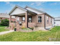 Charming brick home with a cozy covered front porch and landscaped front yard at 304 E Nebraska Ave, Berthoud, CO 80513