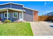 Charming home with gray siding, a brick accent wall, and a well-maintained lawn and driveway at 607 5Th St, Frederick, CO 80530
