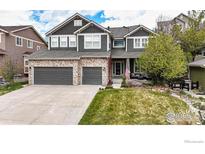 Charming two-story home featuring a stone facade, attached two-car garage and manicured lawn at 7281 Arco Iris Ln, Castle Pines, CO 80108