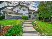 Charming two-story home with a stone and stucco exterior, landscaped front yard, and inviting walkway leading to the front door at 2206 Eagles Nest Dr, Lafayette, CO 80026