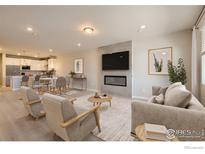 Open-concept living room with a fireplace, modern décor, and seamless flow into the kitchen and dining area at 2732 Bear Springs Cir, Longmont, CO 80503