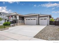 Charming gray home with a covered porch, two-car garage, and well-maintained landscaping at 3022 Merlin Dr, Brighton, CO 80601