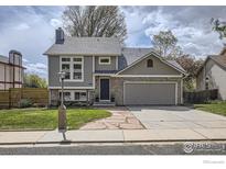 Charming two-story home with a brick facade, gray siding, and a well-maintained front yard at 709 Buchanan Ln, Longmont, CO 80504