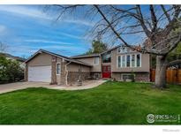 Charming home featuring a well-manicured lawn, brick accents, and a vibrant red front door at 1561 Belmont Dr, Longmont, CO 80503