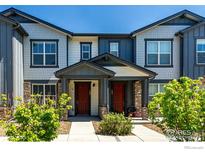 Charming townhome exterior featuring a covered front porch and manicured landscaping under a bright blue sky at 157 Ambrose St, Erie, CO 80516