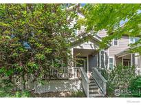 Charming townhome featuring a cozy front porch and neutral siding, framed by lush greenery and a welcoming entrance at 1675 Saratoga Dr, Lafayette, CO 80026