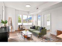 Bright living room with hardwood floors, a green sofa, and large windows showing mountain views at 1707 Walnut St # 205, Boulder, CO 80302