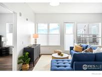Bright living room featuring a blue sofa, modern decor, and large windows with ample natural light at 1707 Walnut St # 307, Boulder, CO 80302