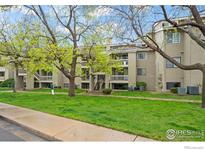 Well-maintained condo building with lush green lawn, trees, and staircase to upper units at 20 S Boulder Cir # 2312, Boulder, CO 80303
