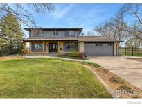 Charming two-story home with a lush green lawn and inviting front porch at 2548 Horseshoe Cir, Longmont, CO 80504