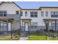 Charming townhome with modern gray and white siding, black trim, and a small fenced front yard with grass and rock landscaping at 2743 Bear Springs Cir, Longmont, CO 80503