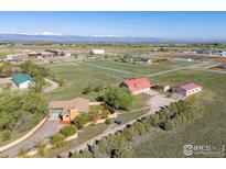 Breathtaking aerial view showcasing the property, large acreage, barn and outbuildings with stunning mountain views at 3117 County Road 14 1/2, Erie, CO 80516