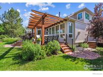 Inviting backyard with a spacious deck, pergola, lush lawn, and mature landscaping at 4059 Nevis St, Boulder, CO 80301