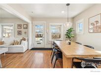 Sunlit dining room featuring a wood table, modern lighting, and hardwood floors, open to the living area at 4511 Bryant St, Denver, CO 80211