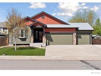 Home exterior with a three-car garage, well-maintained lawn, and stone pillar accents at 9137 Harlequin Cir, Longmont, CO 80504