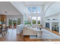 Bright living room with soaring ceilings, large windows, a fireplace, and hardwood floors at 1414 Hoffman Dr, Erie, CO 80516