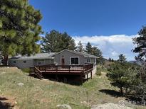 Ranch style home with a large wooden deck surrounded by mature trees and natural landscaping at 258 Post Boy Rd, Boulder, CO 80302