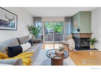Comfortable living room with a gray sofa, fireplace, and sliding glass door to a balcony at 3300 Bridger Trl # 111, Boulder, CO 80301