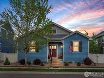 Charming blue home with a red door, American flag, and inviting front yard at 569 Jackson St, Lafayette, CO 80026