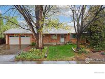 Charming single-story brick home with a well-manicured lawn and mature trees at 6432 Owens St, Arvada, CO 80004