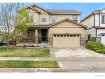 Two-story home featuring a manicured lawn, a two car garage, and a welcoming front porch at 687 Jarvis Dr, Erie, CO 80516