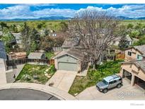 Charming home featuring a large tree, a two-car garage, and lush landscaping with mountain views at 9125 W 95Th Ave, Westminster, CO 80021