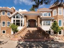Stately stone and stucco home with a grand entrance featuring a terracotta tiled roof and expansive brick staircase at 1189 Rembrandt Rd, Boulder, CO 80302