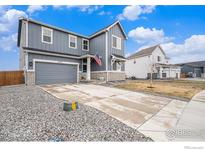 Two-story home featuring a two-car garage, gray siding, brick accents, a concrete driveway, and manicured landscaping at 14762 Charbray St, Mead, CO 80542