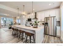Modern kitchen featuring an island with seating, stainless steel appliances, and elegant pendant lighting at 1718 Peak Loop, Broomfield, CO 80023