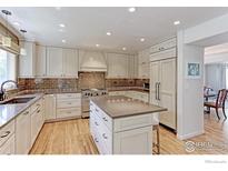 Modern kitchen with custom cabinets, stone counters, stainless appliances, and a kitchen island at 540 Columbine Ave, Broomfield, CO 80020