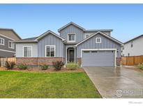 Charming two-story home with gray siding, brick accents, manicured lawn, and a two-car garage at 6732 E 119Th Ave, Thornton, CO 80233